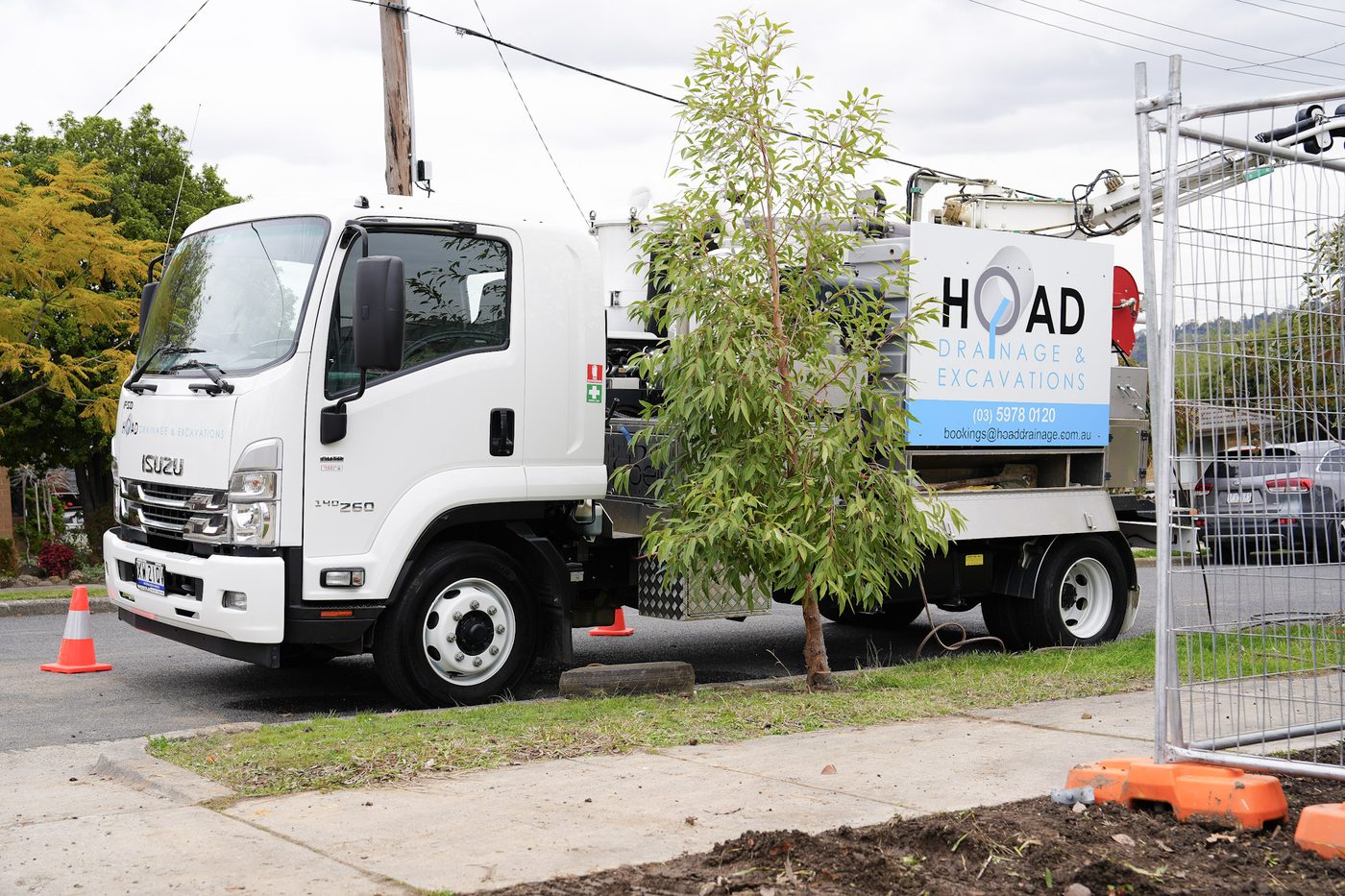 Branded Hoad Drainage Isuzu tip truck parked on site.